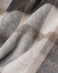 A close-up view of a gray and beige plaid winter scarf, showcasing its cozy winter texture and pattern.