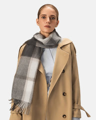 A model wearing a gray and beige plaid winter scarf, showcasing its stylish design and cozy texture.