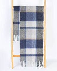 A gray and blue plaid winter scarf draped over a wooden ladder, showcasing its stylish pattern.