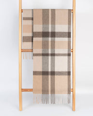 A gray and coffee plaid scarf draped over a wooden ladder, showcasing its stylish pattern.