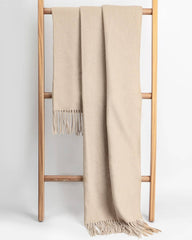 A beige winter scarf draped over a wooden ladder, creating a warm, inviting atmosphere.