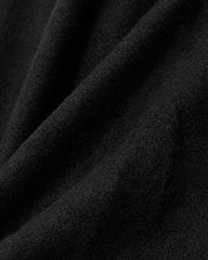 A black scarf resting on a wooden ladder, with a winter scarf placed beside it, evoking a warm, seasonal atmosphere.