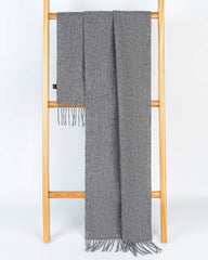A grey winter scarf elegantly draped over a wooden stand, showcasing its soft texture and cozy appeal.