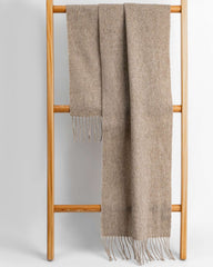 A khaki winter scarf elegantly draped over a wooden stand, showcasing its soft texture and cozy appeal.