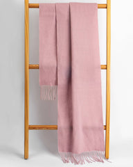 A pink winter scarf elegantly draped over a wooden stand, showcasing its soft texture and cozy appeal.