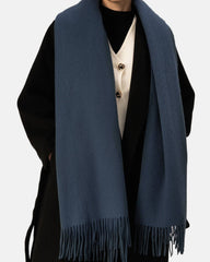A woman elegantly draped in a blue scarf, showcasing a stylish accessory that enhances her outfit.