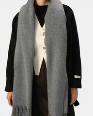 A woman in a grey scarf and black coat, exuding elegance and warmth in her attire.