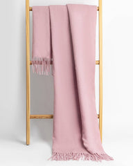 A pink women's scarf and shawl draped elegantly over a wooden stand.