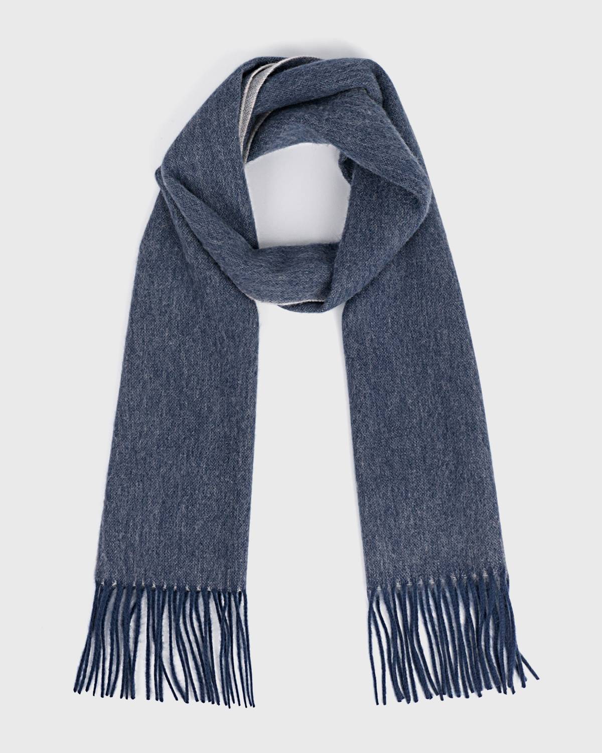 A reversible blue wool scarf with fringes, showcasing a soft texture and elegant design.