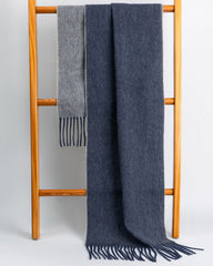 A blue and grey reversible scarf displayed elegantly on a wooden rack, showcasing its dual color design.