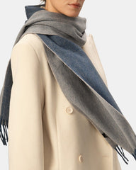 A woman elegantly draped in a reversible blue and grey scarf, showcasing its versatility and style.