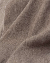 A close-up view of a soft khaki wool scarf, showcasing its texture and warmth in a cozy setting.