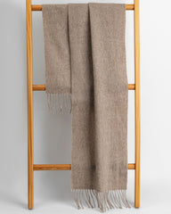 A khaki scarf placed on a wooden ladder, emphasizing the warm tones of the scarf against the ladder's texture.