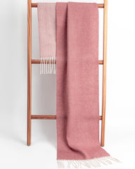 A pink reversible scarf displayed on a wooden ladder, creating a warm and inviting atmosphere.