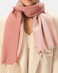 A woman in a white coat and a pink reversible scarf, showcasing a stylish and vibrant look.