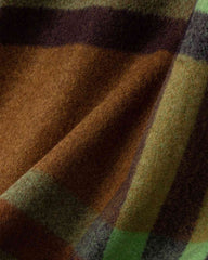 Close-up of a cozy plaid scarf featuring green, brown, and black patterns, perfect for adding warmth to any space.