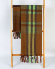 A cozy brown and green plaid scarf draped over a rustic wooden ladder, adding warmth to the scene.