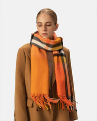 A woman with a bright orange scarf wrapped around her neck, smiling warmly against a soft background.