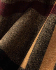 Close-up of a cozy plaid scarf featuring red, brown, and black patterns, perfect for adding warmth to any space.