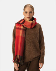 A woman stylishly draped in a red and brown plaid scarf, adding a cozy touch to her outfit.