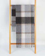 A gray and beige plaid winter scarf draped elegantly over a wooden ladder, showcasing its winter warmth and style.