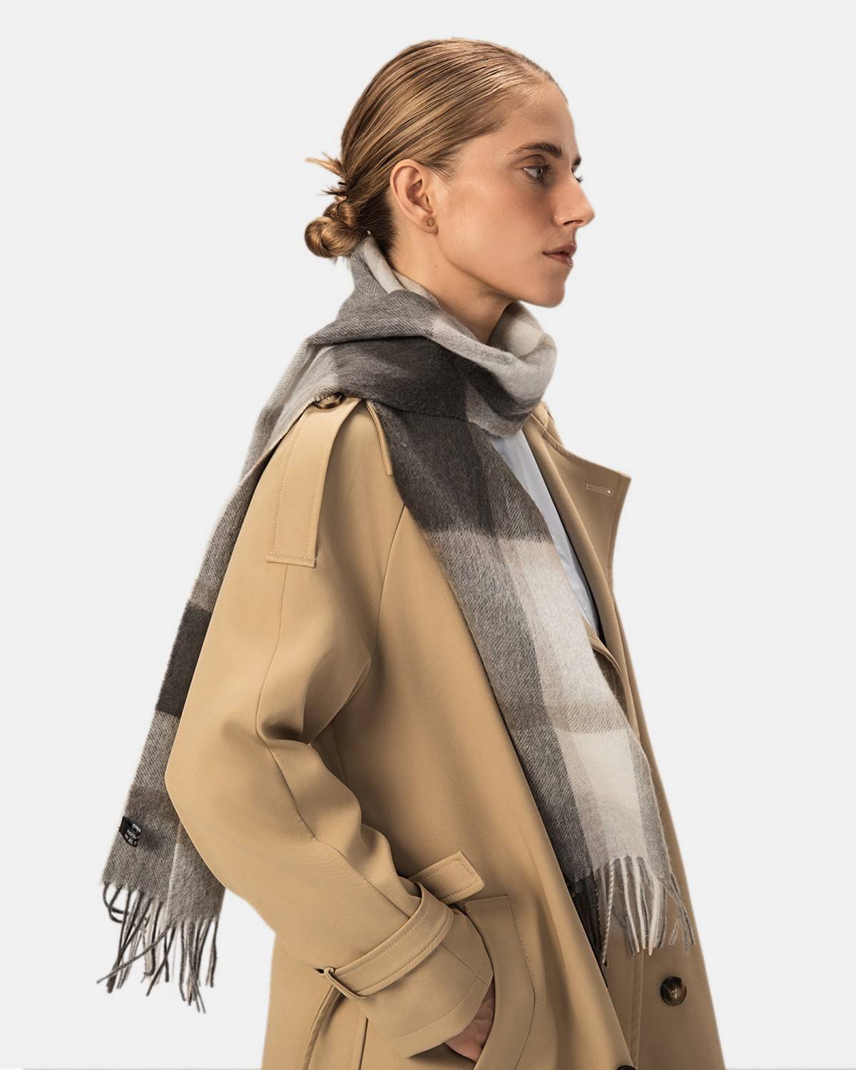 A model presents a cozy wool scarf in a gray and beige plaid design, ideal for winter styling.