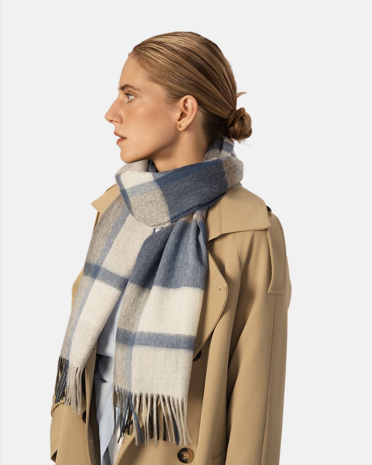 A woman wears a blue and gray winter  scarf, showcasing its stylish design and elegant drape.