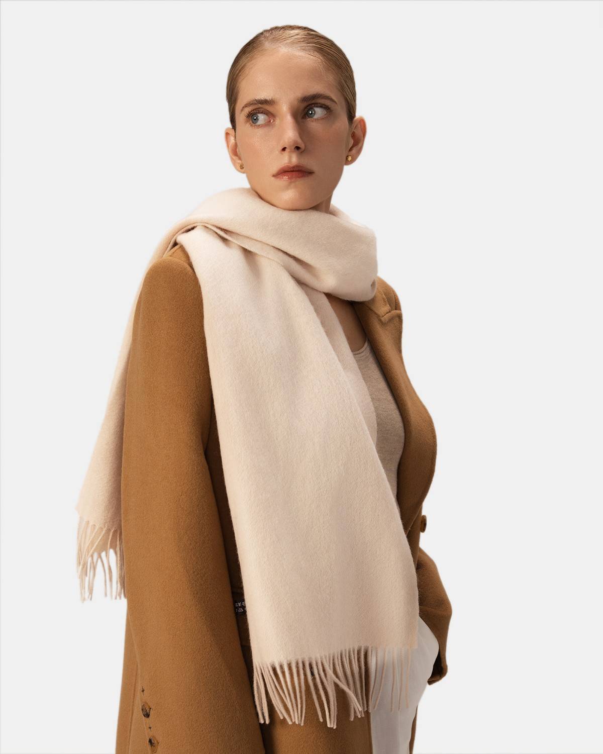 A model showcases a luxurious wool scarf with fringes, perfect for winter warmth and style.