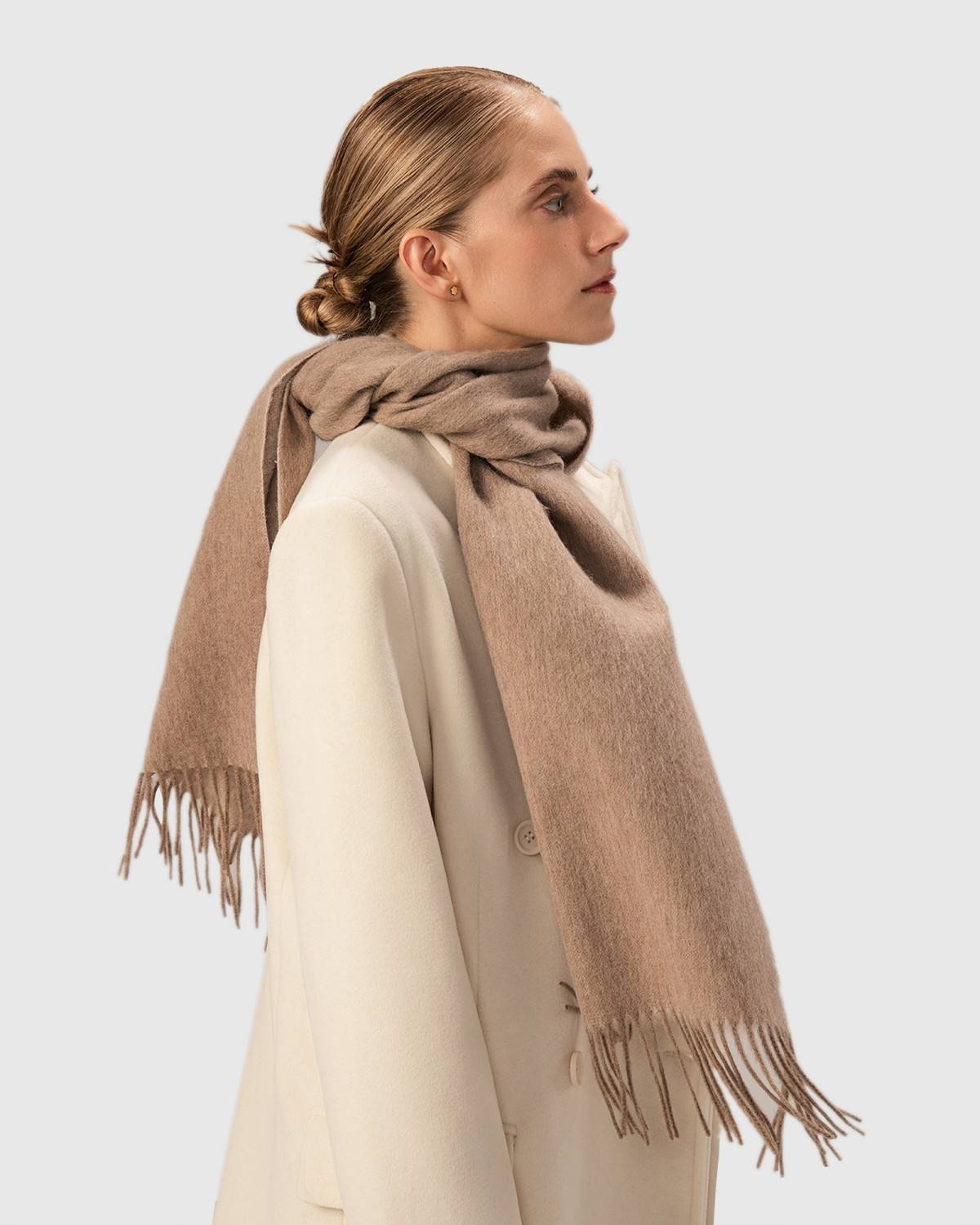A khaki winter scarf made of wool is displayed on a model, highlighting its soft texture and warmth.