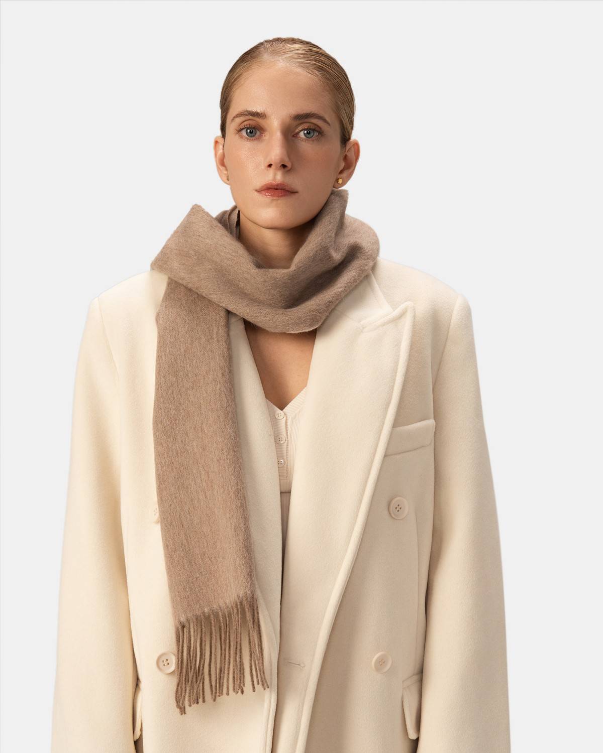 A model displays a khaki wool scarf featuring a fringed edge, highlighting its luxurious texture and winter appeal.