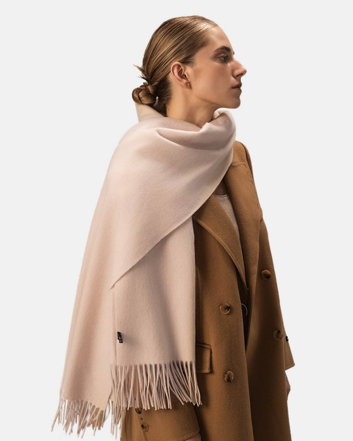 A model showcases a beige wool scarf, elegantly draped as a shawl, highlighting its softness and style for women.