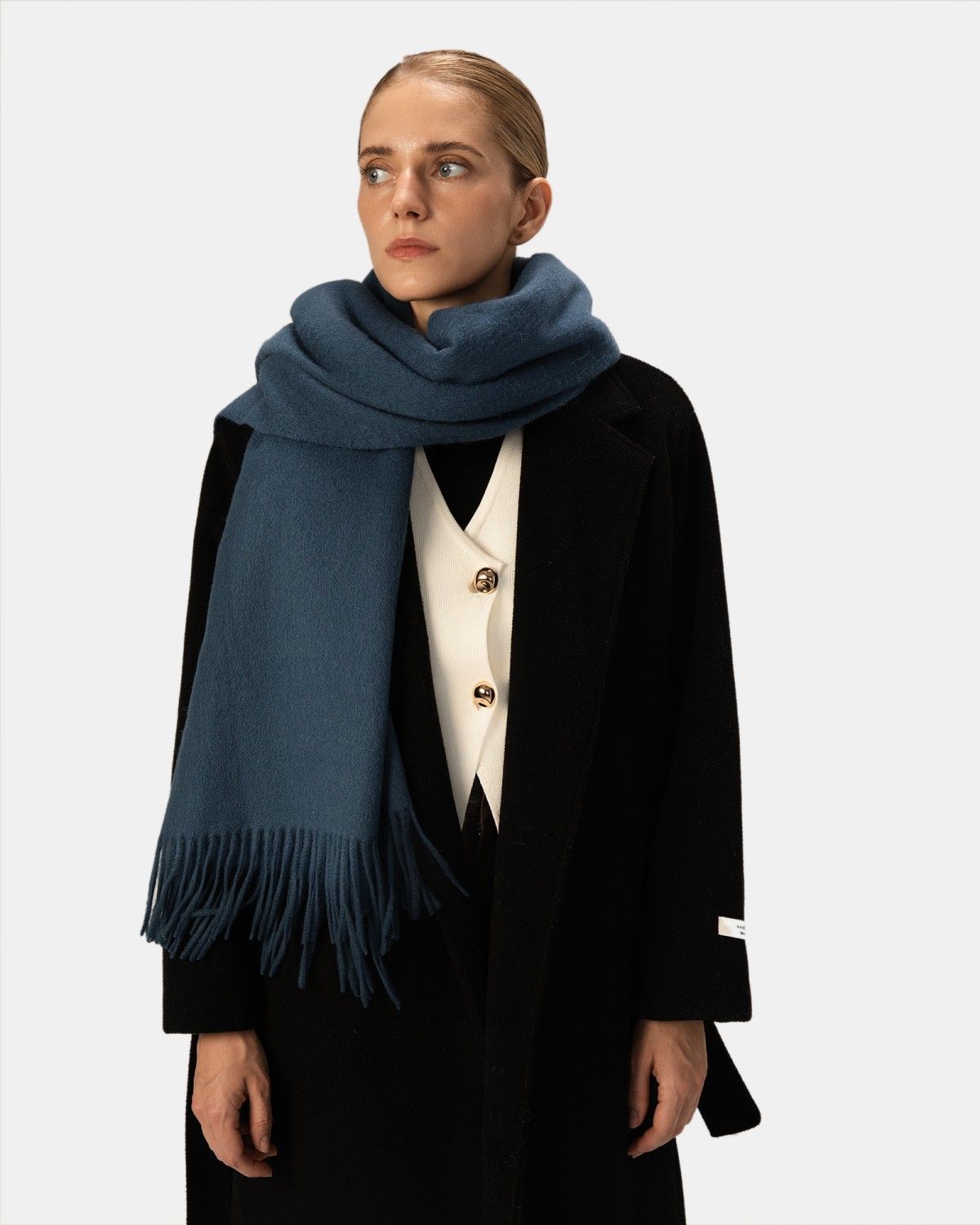 A model elegantly showcases a soft blue cashmere scarf, highlighting its luxurious texture and vibrant color.