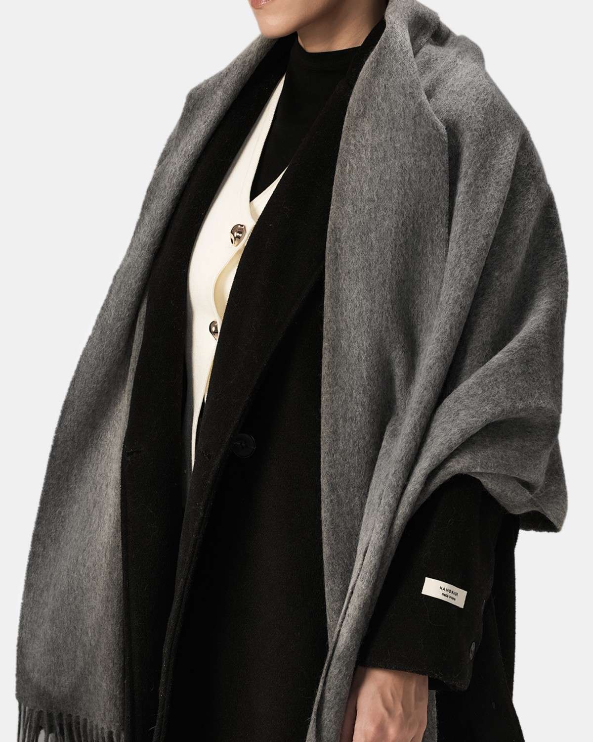 A woman in a black coat and gray shawl, exuding elegance and warmth in her winter attire.