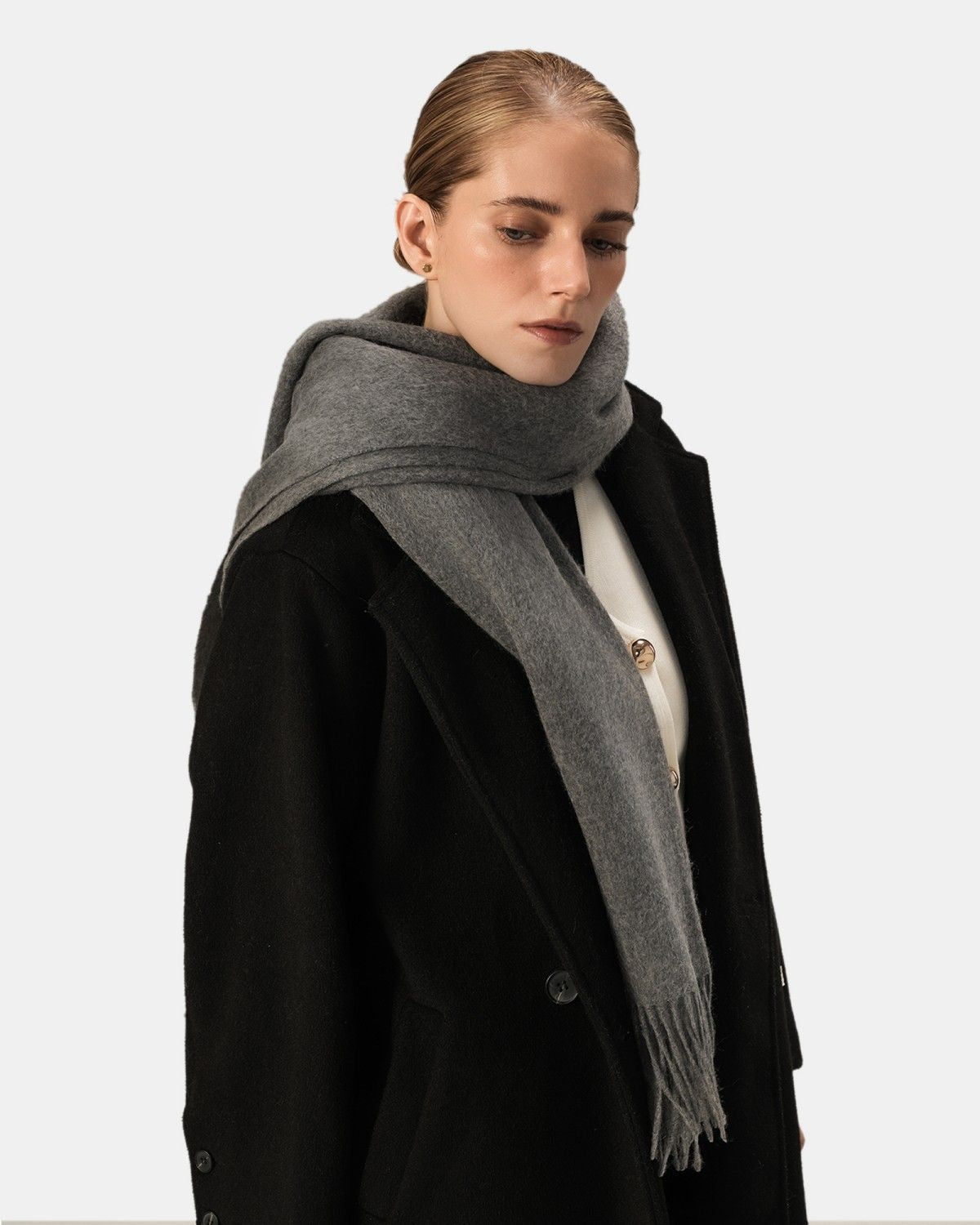 A woman wearing a black coat paired with a gray scarf, embodying sophistication in cold weather fashion.