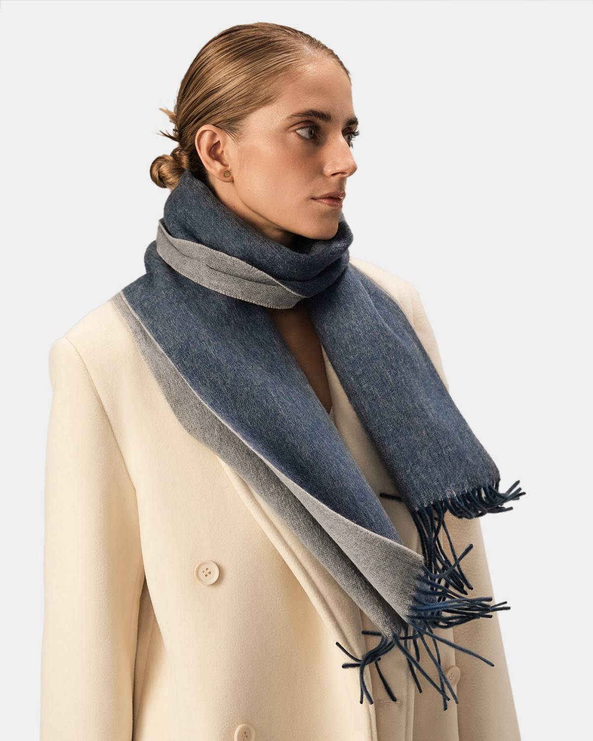 A model displays a reversible scarf made from two different colors of wool, highlighting its unique design and versatility.