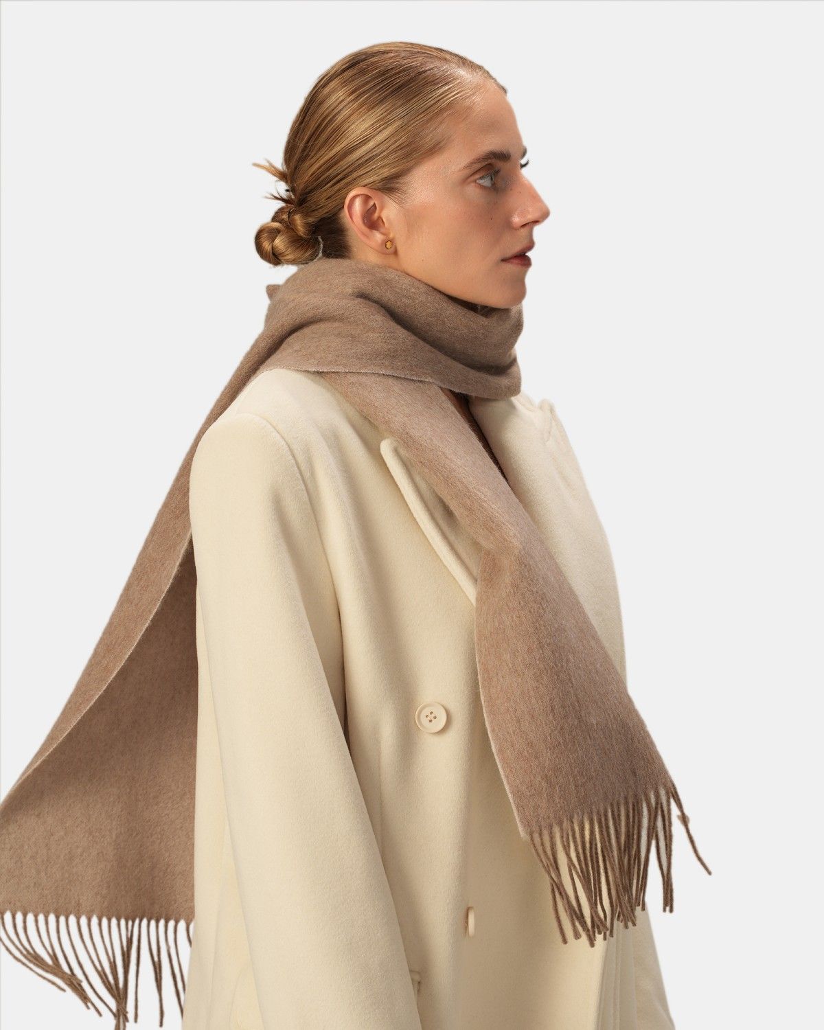 A model displays a khaki reversible scarf made from wool, highlighting its softness and stylish appeal.