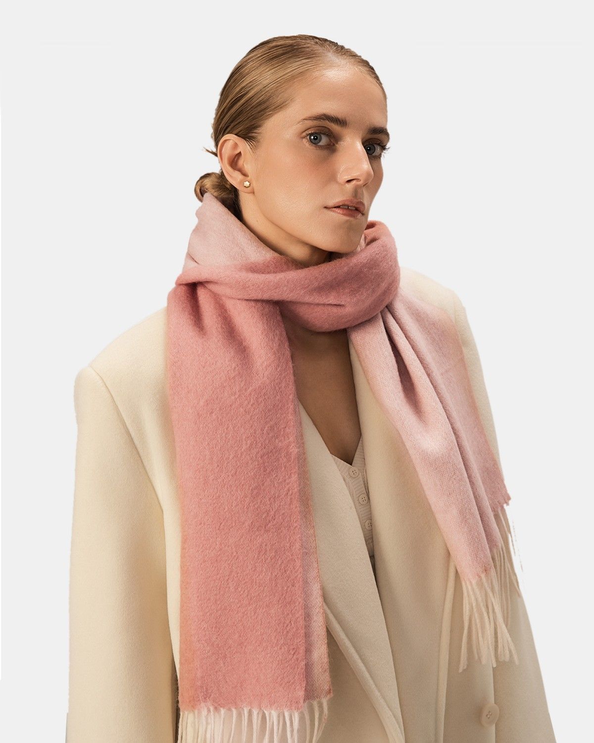 A model showcases a reversible pink scarf crafted from luxurious wool, highlighting its elegant texture.