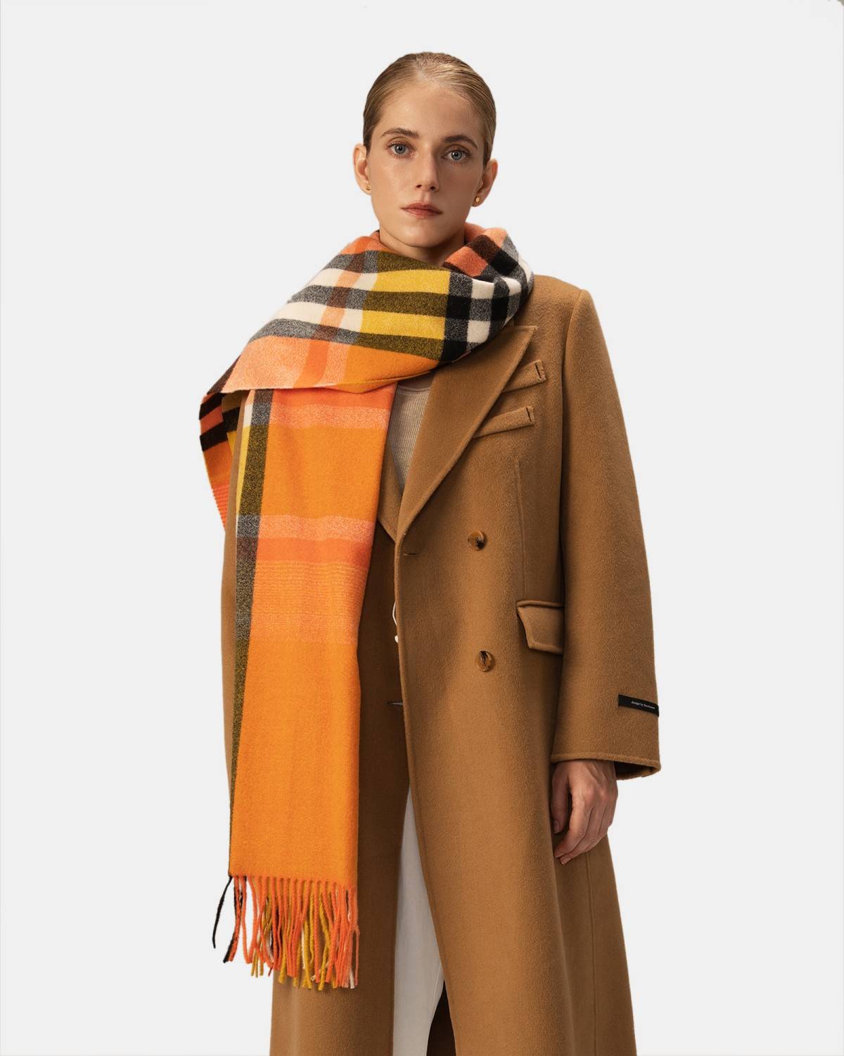 A model showcases a classic orange check scarf, adding a pop of color to their stylish outfit.