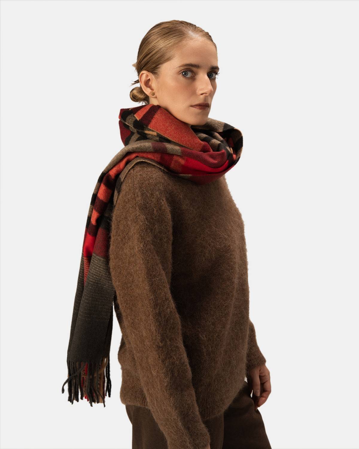 A soft scarf showcasing a classic red, black, and brown plaid pattern, perfect for keeping warm and fashionable.